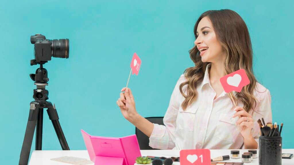 Explosão do Marketing de Influenciadores: Tendências para 2025 com criadora de conteúdo sorrindo enquanto grava vídeo para redes sociais segurando ícones de curtidas em um estúdio colorido.